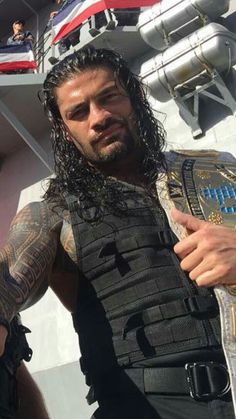 a man with long hair and tattoos holding a wrestling belt
