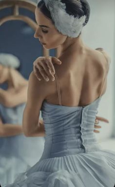 a woman in a blue dress looking at herself in the mirror