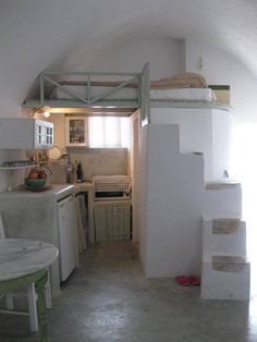 a small kitchen and dining area in an attic style home with white walls, tile flooring and stairs leading up to the upper level