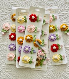 small crocheted flower clips in assorted colors on a white table with lace