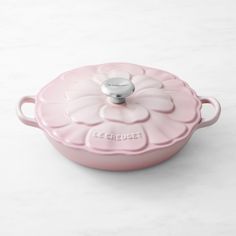 a pink casserole dish with a flower design on the front and bottom, sitting on a white surface