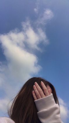 a woman with her hands on her face looking up into the sky at a kite flying in the air