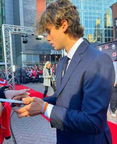 a man in a suit signing autographs for fans