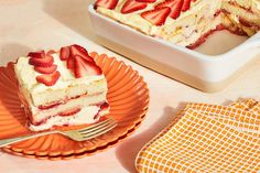 a piece of cake on an orange plate with a fork next to it and a bowl of strawberries in the background