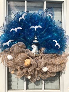 a blue wreath with seagulls and seashells hanging on the front door