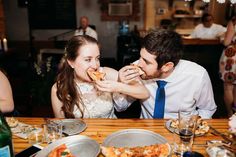 a man and woman sitting at a table eating pizza