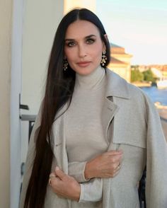 a woman with long hair wearing a gray coat