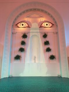 an archway with plants and eyes on the wall in front of it is lit by lights