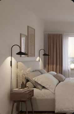 a white bed sitting next to a window with two lamps on each side of it