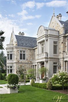 a large stone house with many windows and bushes