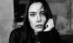 a black and white photo of a woman with her hand on her chin looking at the camera