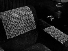 a black and white photo of a chair with a crocheted seat cover