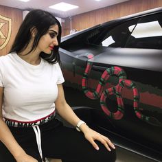 a woman sitting on the ground next to a car with snake painted on it's side