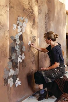 a woman is painting flowers on the wall