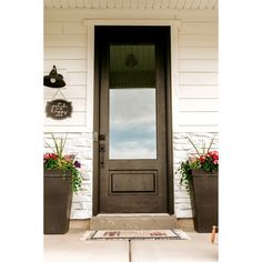 two planters with flowers are on the front porch of a house that is painted white