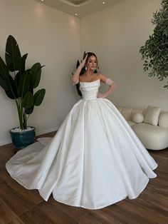 a woman in a white wedding dress posing for the camera with her hands on her head