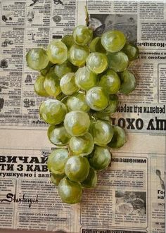 a bunch of green grapes sitting on top of a newspaper