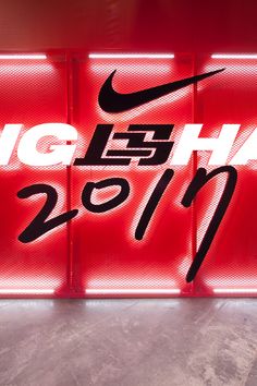 the nike logo is lit up in front of a red sign that says hong kong