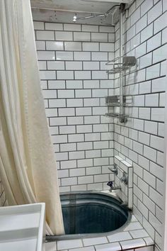 a bath tub sitting inside of a bathroom next to a white shower curtain and tiled walls