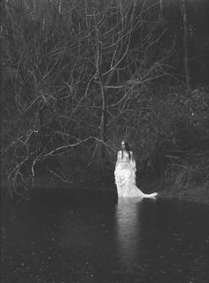 a woman is standing in the water near trees