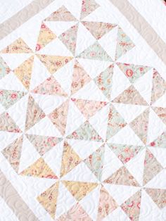 a close up of a quilted table topper on a white surface with pink and yellow flowers