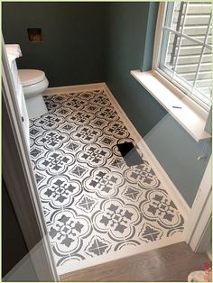 a white toilet sitting next to a window in a bathroom on top of a hard wood floor