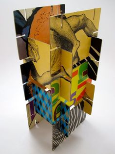 an abstract sculpture made out of multiple pieces of paper and colored images on the side