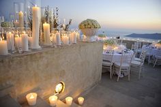 a table with candles and flowers on it next to a wall filled with vases