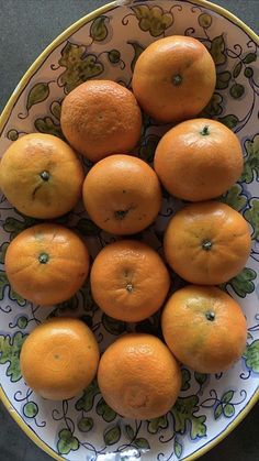 a bowl filled with oranges on top of a table