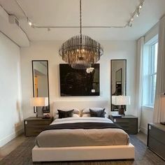 a large bed sitting in a bedroom under a chandelier