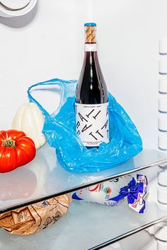 a bottle of wine sitting on top of a glass table next to some vegetables and fruit