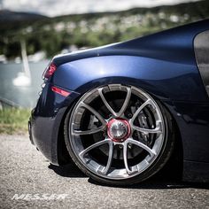 the front end of a blue sports car with chrome rims and red brake pads