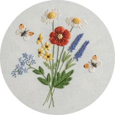 a white circle with flowers and butterflies on it's side, embroidered onto the front