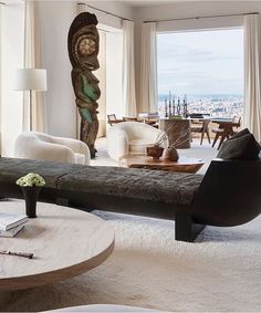 a living room filled with lots of furniture and a large window overlooking the cityscape