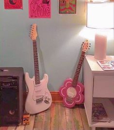 two guitars are sitting next to each other in front of a wall with posters on it