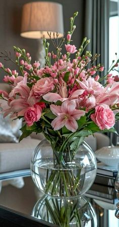 a vase filled with pink flowers sitting on top of a table next to a couch