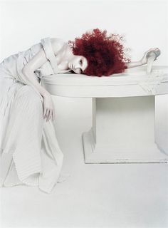 a woman with red hair laying on a white bench