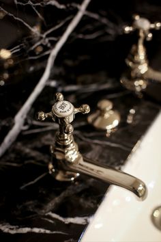 the faucet in the bathroom is made of brass and has a black marble counter top