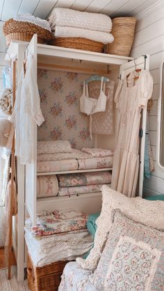 an open closet filled with lots of white sheets and blankets next to a bed in a room