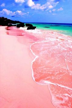 the beach is pink and green with waves coming in from the water on top of it