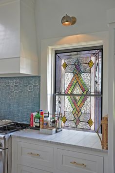 a kitchen with a stove top oven next to a stained glass window