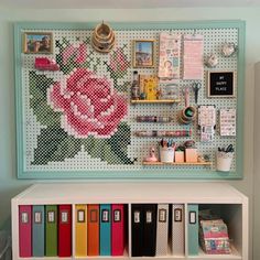 a white shelf topped with lots of crafting supplies next to a wall mounted pegboard