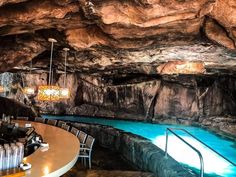 a restaurant with tables and chairs next to a pool in the middle of a cave