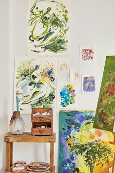 an art studio with paintings on the wall and wooden table in front of it,