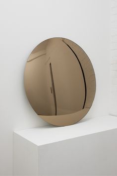 a round mirror sitting on top of a white shelf