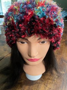 a mannequin head wearing a multicolored hat on top of a wooden table