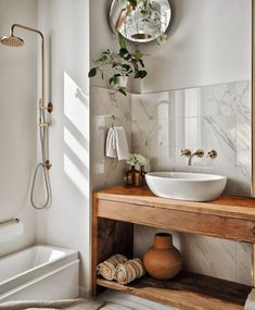 a bathroom with a sink, mirror and bathtub next to a shower head mounted on the wall