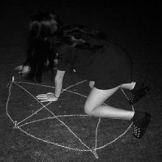 a woman kneeling down on top of a chalk drawing in the dark with her hands behind her head