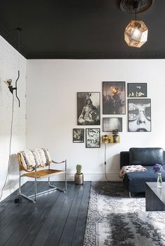 a living room filled with furniture and pictures hanging on the wall above a wooden floor