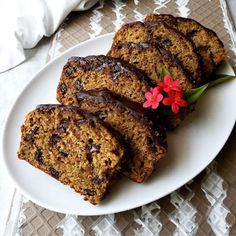 slices of chocolate - covered banana bread on a white plate with a red flower in the middle